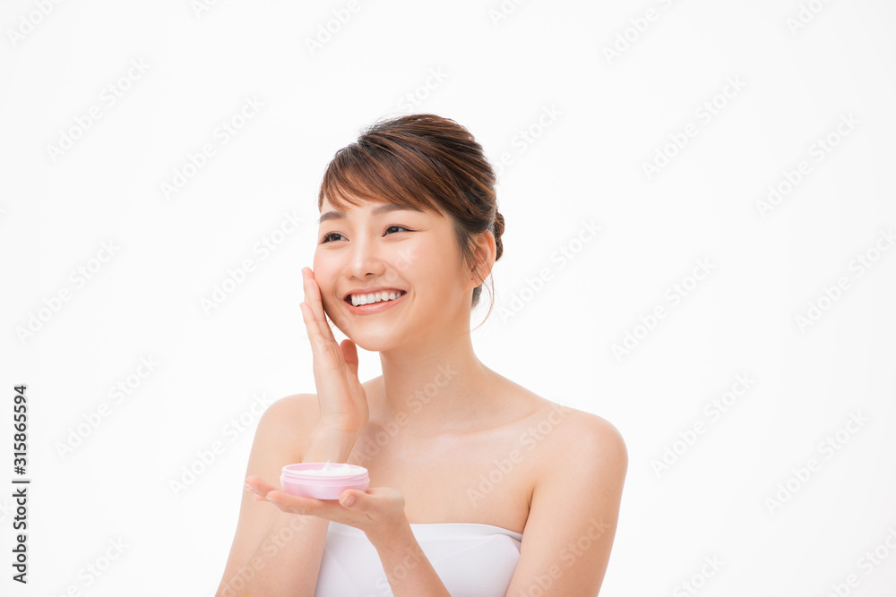 Beauty concept. Asian girl is applying cream on her face. Beauty concept. Asian girl is applying cream on her face.