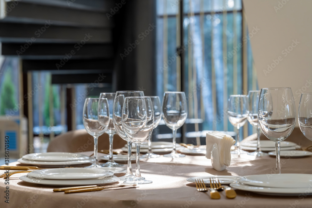 Beautiful table setting with glasses, plates and napkins. General form.