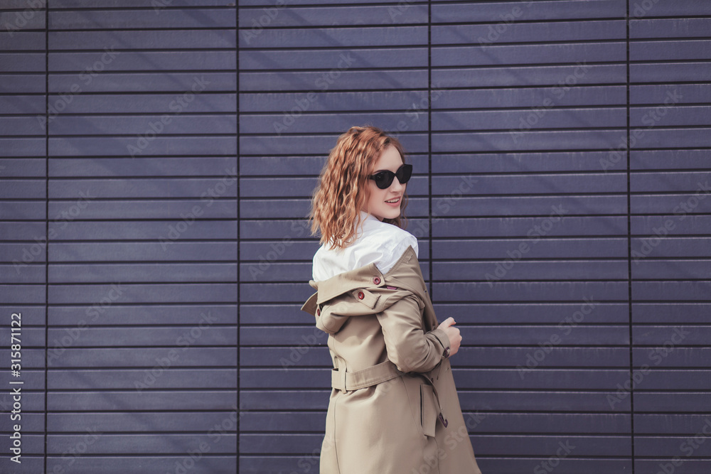 Fototapeta premium Stylish happy young woman wearing trendy coat and sunglasses