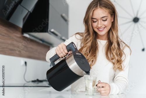 Billede på lærred Photo of beautiful happy woman smiling and making tea
