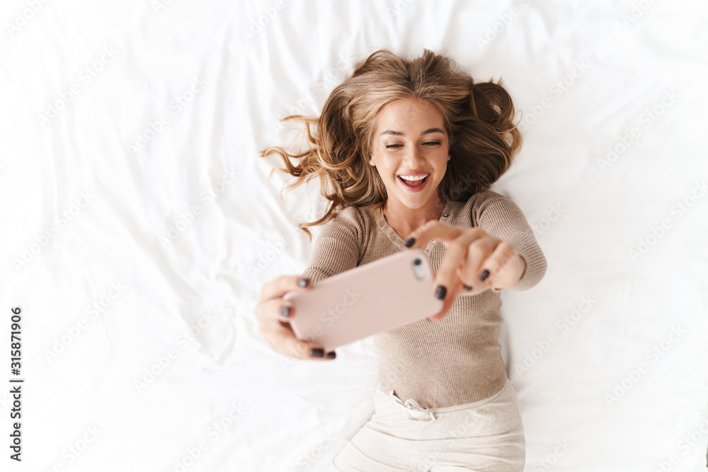 Photo of young smiling woman taking selfie photo on cellphone Photo of young smiling woman taking selfie photo on cellphone