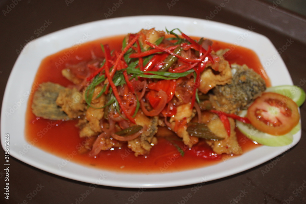 The best fried fish with padang sauce and vegetables on top