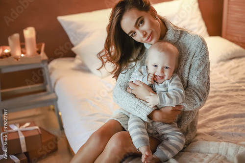 Mom and son baby in pajamas play and indulge in the room.
