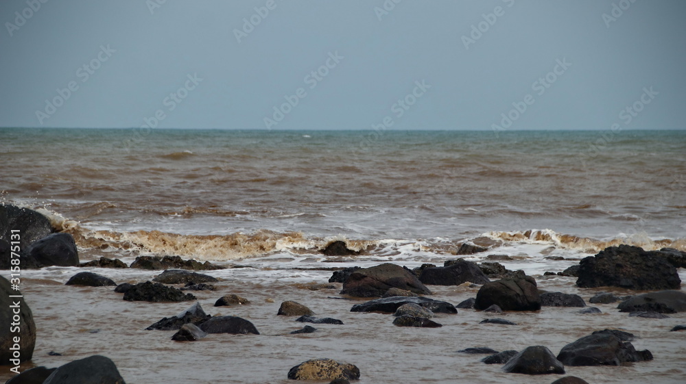 Fototapeta premium Fierce waves on the beach that hit the black coral, with selective focus