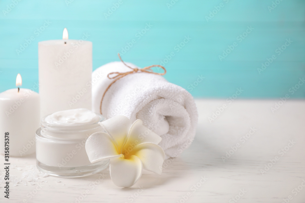 Composition with cream and burning candles on white wooden table. Spa treatment