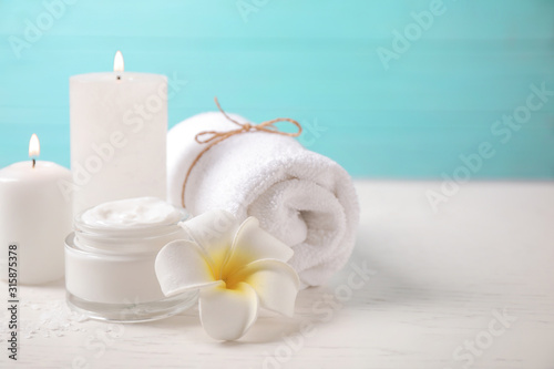 Composition with cream and burning candles on white wooden table. Spa treatment