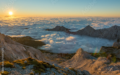 Spectacular morning mountain panorama with sun raising above sea of clouds.
