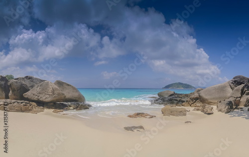 view of many arch rocks on white sand beach with blue green sea and cloudy sky background, Similan island, Mu Ko Similan National Park, Phang Nga, southern of Thailand.