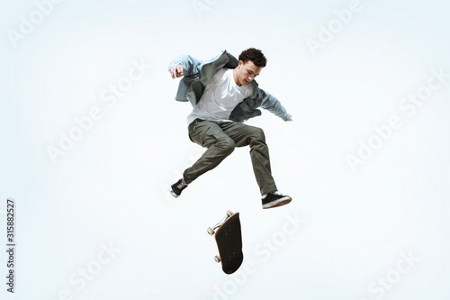 Wallpaper Mural Caucasian young skateboarder riding isolated on a white studio background. Man in casual clothing training, jumping, practicing in motion. Concept of hobby, healthy lifestyle, youth, action, movement. Torontodigital.ca