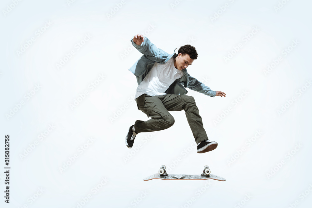 Caucasian young skateboarder riding isolated on a white studio background. Man in casual clothing training, jumping, practicing in motion. Concept of hobby, healthy lifestyle, youth, action, movement. Caucasian young skateboarder riding isolated on a white studio background. Man in casual clothing training, jumping, practicing in motion. Concept of hobby, healthy lifestyle, youth, action, movement.