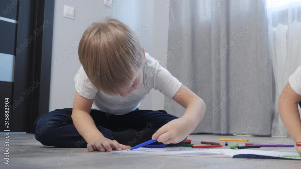 children draw with felt-tip lifestyle pens in an album. little boy and girl concept childhood brother and sister play paint on the floor with colored markers children draw with felt-tip lifestyle pens in an album. little boy and girl concept childhood brother and sister play paint on the floor with colored markers