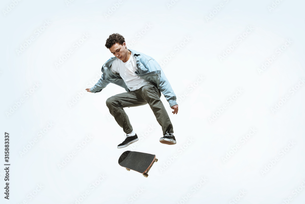 Caucasian young skateboarder riding isolated on a white studio background. Man in casual clothing training, jumping, practicing in motion. Concept of hobby, healthy lifestyle, youth, action, movement. Caucasian young skateboarder riding isolated on a white studio background. Man in casual clothing training, jumping, practicing in motion. Concept of hobby, healthy lifestyle, youth, action, movement.