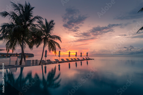 Fototapeta Naklejka Na Ścianę i Meble -  Beautiful poolside and sunset sky. Luxurious tropical beach landscape, deck chairs and loungers and water reflection.