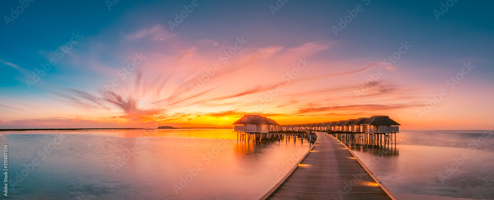 Fototapeta Zachód słońca na wyspie Malediwy, luksusowy wille wodne i drewniany pomost. Piękny niebo, chmury i plażowy tło dla wakacje wakacje i podróży pojęcia