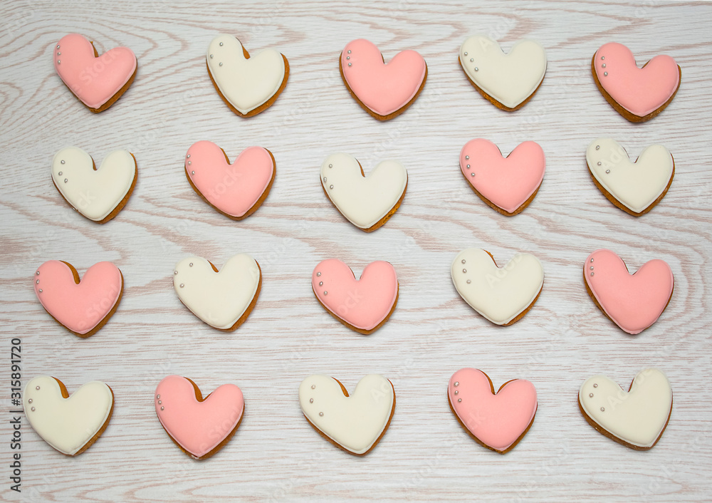 Valentine heart cookies on wooden table, pink and white.