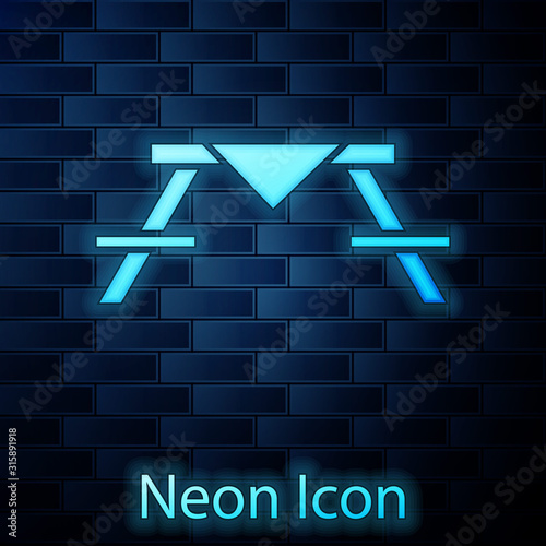 Glowing neon Picnic table with benches on either side of the table icon isolated on brick wall background. Vector Illustration