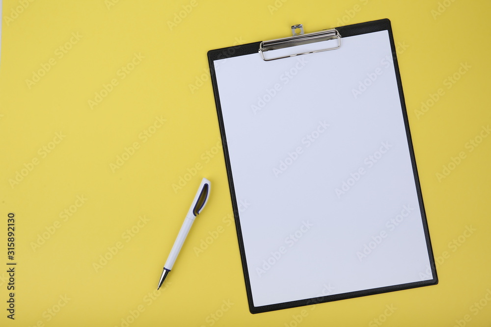 clipboard and pen flat lay on yellow background with copy space clipboard and pen flat lay on yellow background with copy space