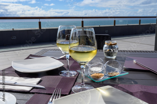 Table served for dinner on outside terrace with glasses of cold white wine and sea view