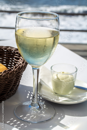 Summer holiday on sea, drinking white wine on outdoor terrace with sea view in sunny day
