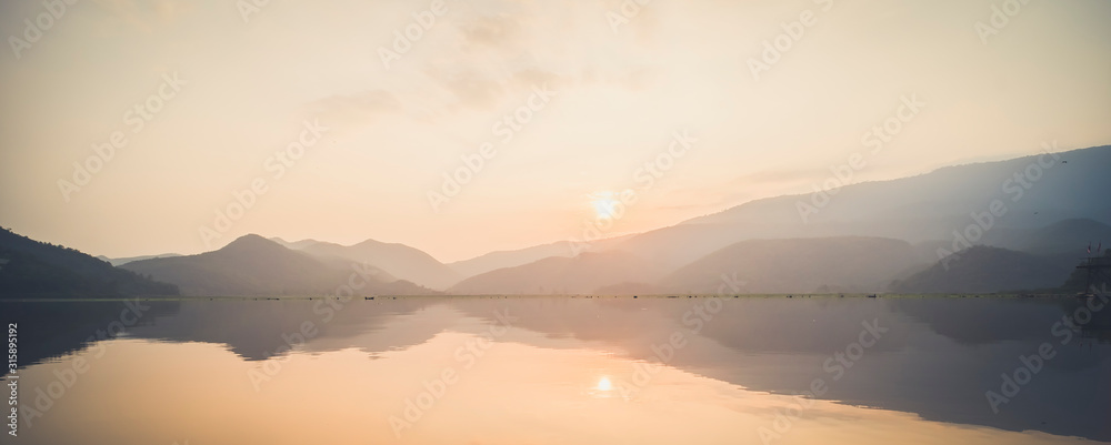 Mountain lake with perfect reflection at sunrise. beautiful landscape with pink pastel sky with hills on background and reflected in water. Nature lake landscape