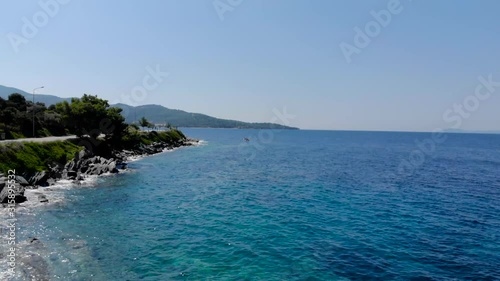 Drone aerial shot of small wooden fishing boat in crystal clear blue waters of Greece coastline.