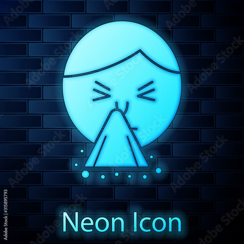 Glowing neon Man holding handkerchief or napkin to his runny nose icon isolated on brick wall background. Coryza desease symptoms. Vector Illustration