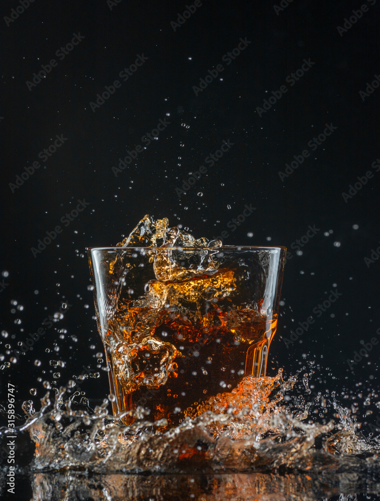 Glass of whiskey with splash isolated on black background Glass of whiskey with splash isolated on black background