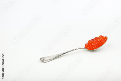 red caviar on a spoon on white background with copy space