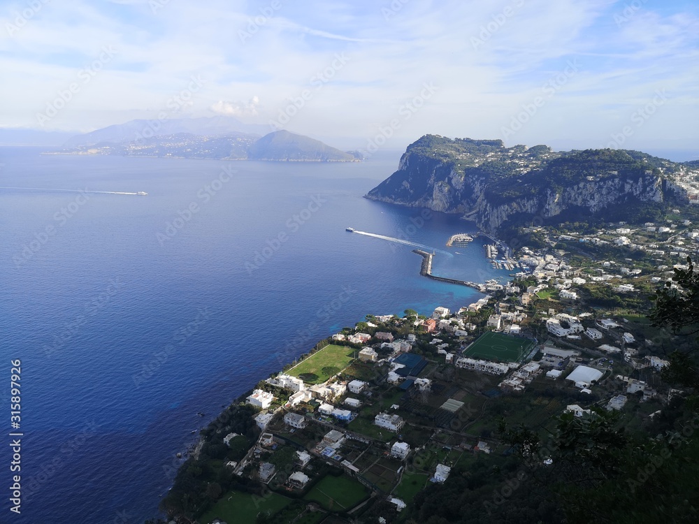 View of the main harbour of Capri Island from the top, with the Amalfi coast at the backround