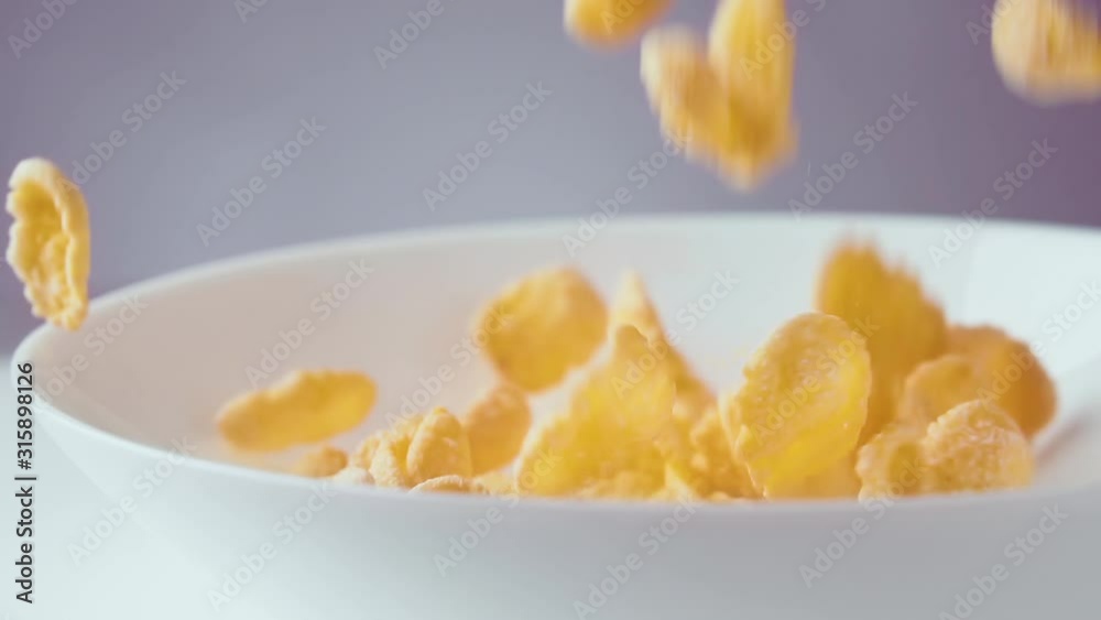 Corn flakes falling in bowl, slow motion. Healthy cereal breakfast, close up. Corn flakes falling in bowl, slow motion. Healthy cereal breakfast, close up.