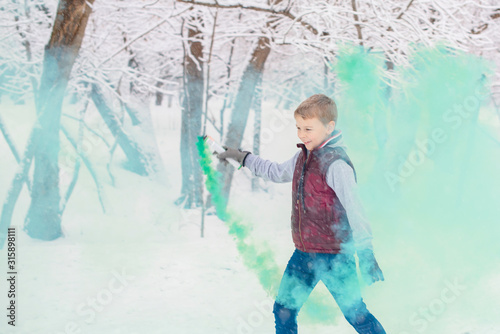 boy with a colored smoke bomb on the street in winter in a snowfall