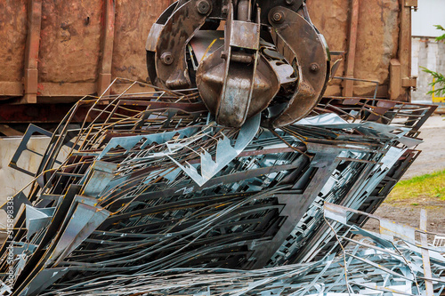 Fotografie A grapple truck loads scrap industrial metal for recycling.