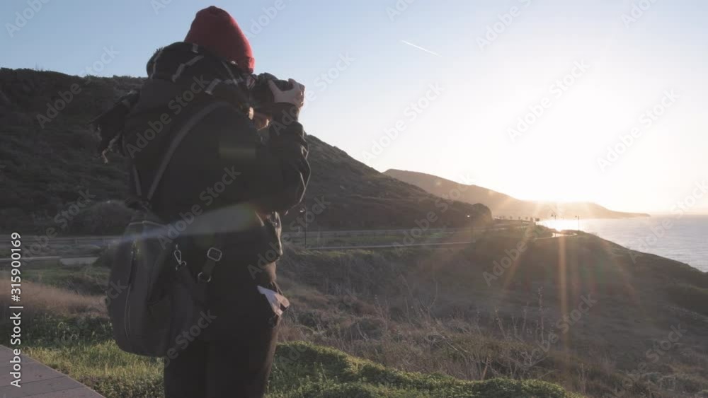 Young woman photographing landcape at sunset