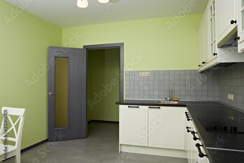 Kitchen room with exit. White wood kitchen unit