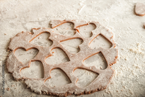 The process of making gingerbread. Flat lay flour heart dough. Texture of the dough for cookies close-up. Gingerbread dough on February 14, flour, rolling pin and copy space. photo