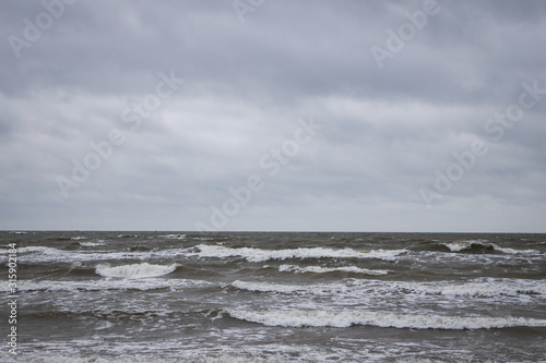 Seaside view of Baltic sea waves on a cloudy and stormy winter day near beach. Photo taken in Latvia.