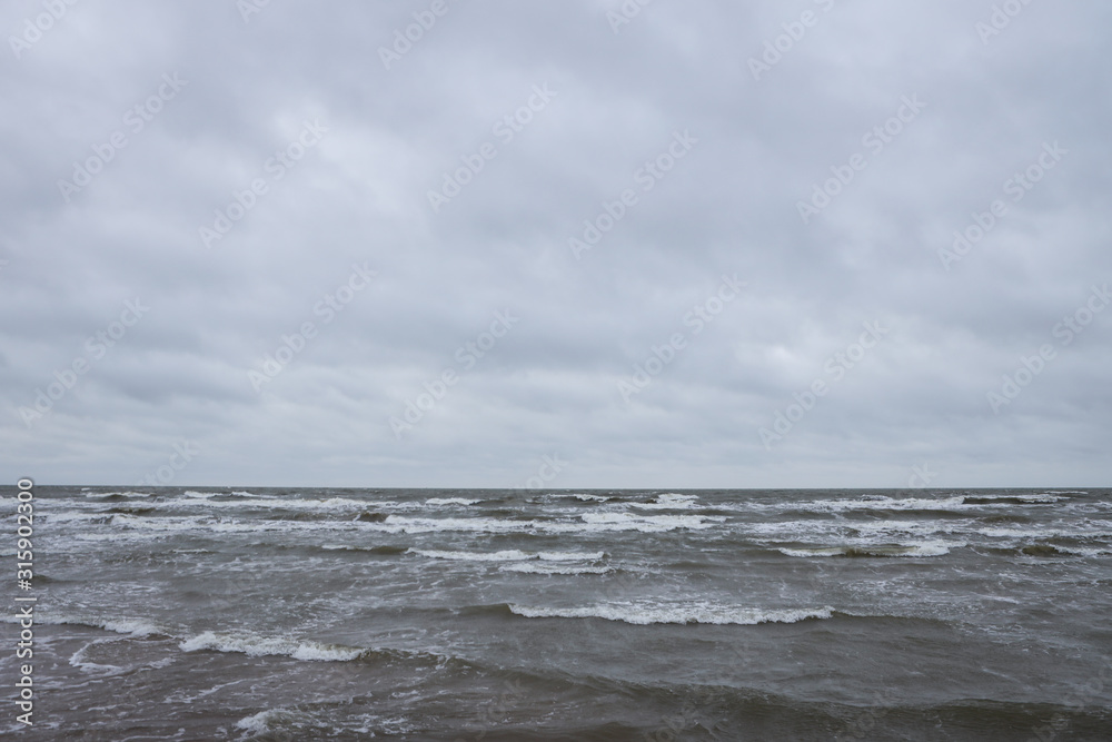 Seaside view of Baltic sea waves on a cloudy and stormy winter day near beach.