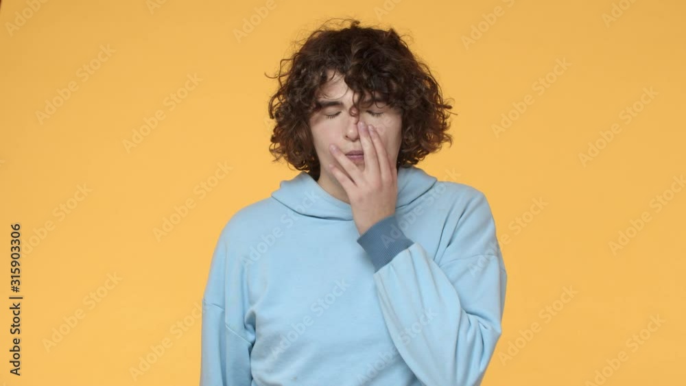 Slow-motion annoyed and fed up young curly guy listen friend lame story, dumb mistake, punch himself at forehead, make facepalm and sighing irritated, give up, looking embarrassed, yellow background Slow-motion annoyed and fed up young curly guy listen friend lame story, dumb mistake, punch himself at forehead, make facepalm and sighing irritated, give up, looking embarrassed, yellow background