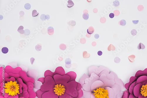 Fototapeta Naklejka Na Ścianę i Meble -  top view of paper cut pink and violet flowers near confetti isolated on white