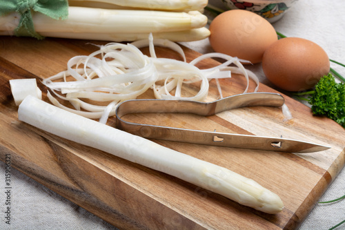 Bunch of fresh uncooked white asparagus and peeler knife, how to peel asparagus vegetables photo