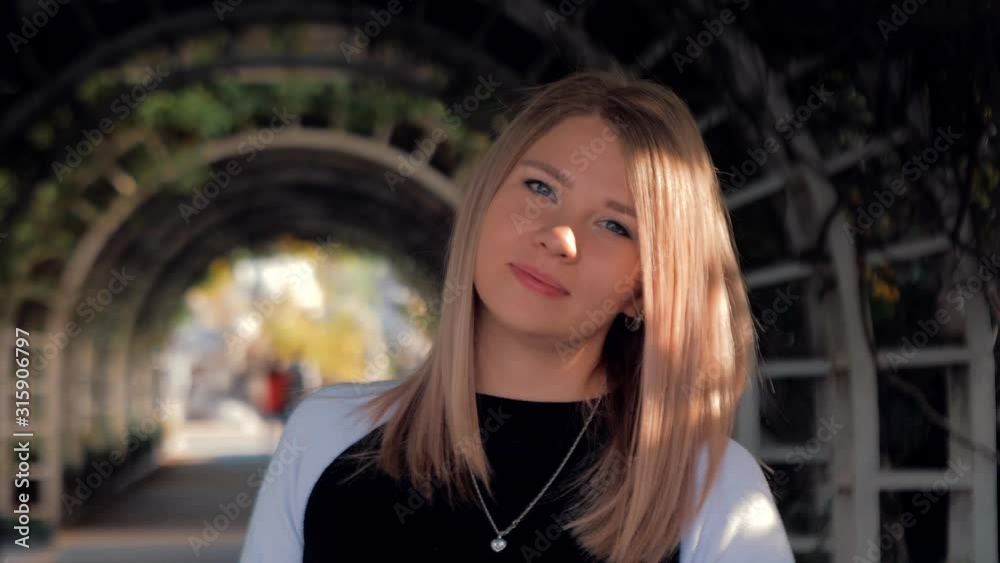 Portrait of beautyful blonde girl , looking at the camera in the archway in park during sunset. Portrait of beautyful blonde girl , looking at the camera in the archway in park during sunset.
