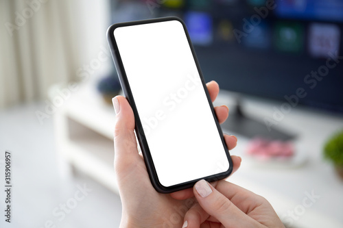 female hands holding phone with isolated screen background of TV © DenPhoto