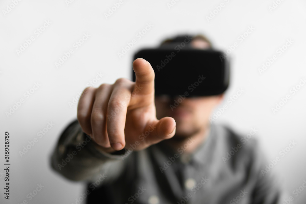 Young bearded man with virtual reality glasses trying to touch something or tap some thing in front of what he seeing. Modern technologies. The concept of future technology.