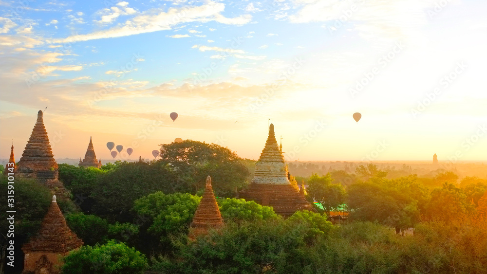 Sunrise in Bagan Archeologial Zone, Myanmar top view with hot air ballooons flying on a horizont. View from a pagoda rooftop