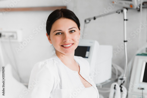 Closeup portrait of arrtractive smiling medical student in scrubs. Hospital background. Healthcare concept.
