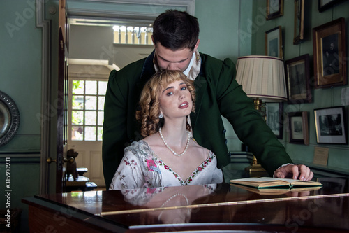 Obraz na plátne Vintage couple in period costume sitting around piano playing tunes with man kis