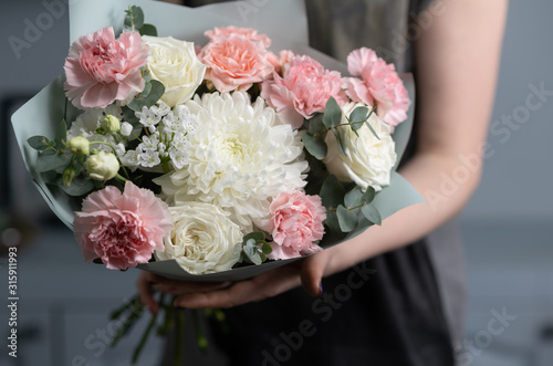 Close-up flowers in hand. Florist workplace. Woman arranging a bouquet with roses  chrysanthemum  carnation and other flowers. A teacher of floristry in master classes or courses