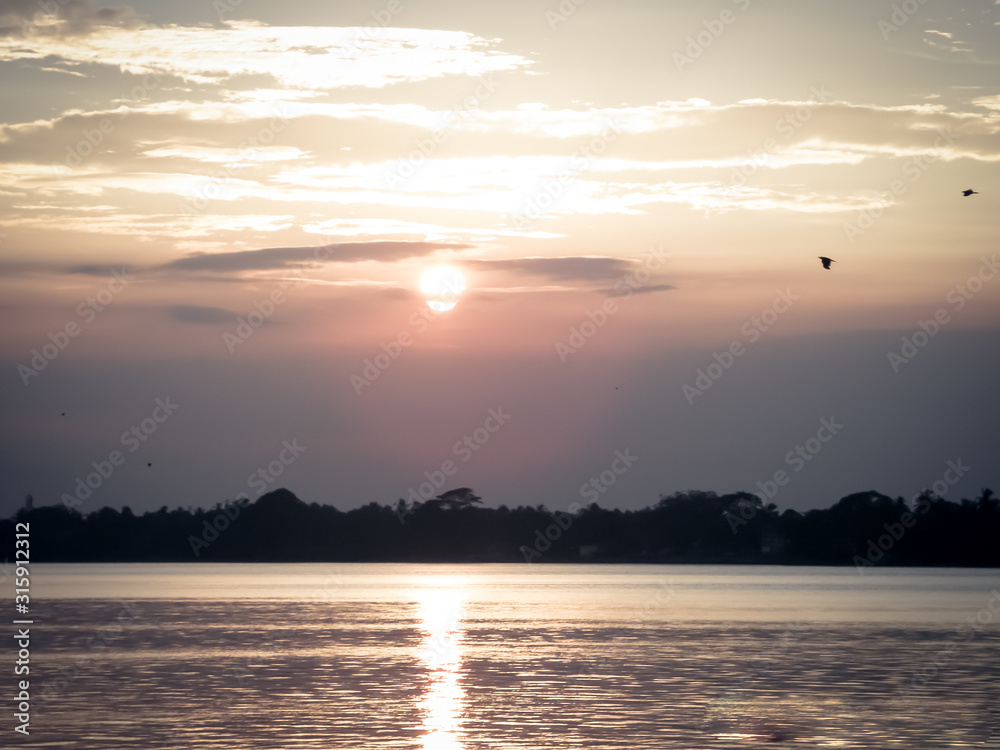 Naklejka premium The sun in the sky in the evening, just before the sun goes down in the west. Evening sunset sky dark, red yellow color. Dusk time in summer. Landscape Scenery. Beauty in nature background.
