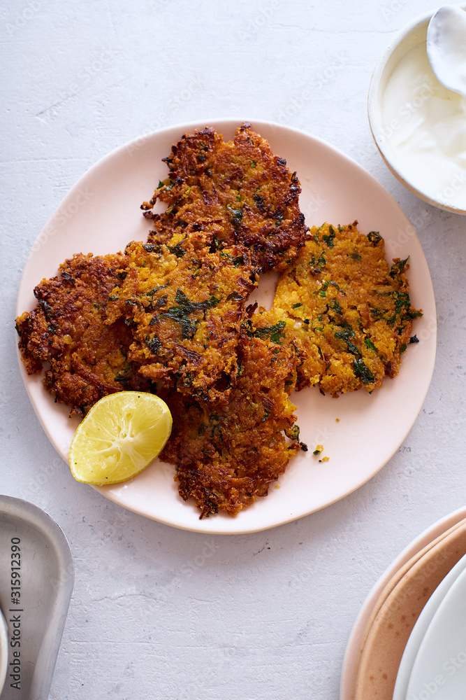 Flatlay with potato latkes with lemon and yoghurt on white background. Traditional israeli festive cuisine. Flatlay with potato latkes with lemon and yoghurt on white background. Traditional israeli festive cuisine.