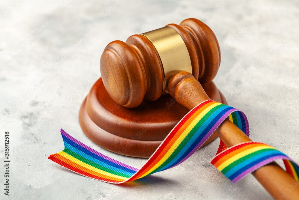 Judge gavel and rainbow ribbon of LGBT pride on gray background
